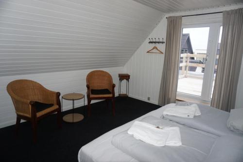 a bedroom with a bed and two chairs and a window at B&B by the Sea Hirtshals in Hirtshals