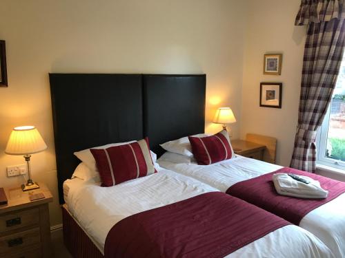 two beds in a hotel room next to a window at Clayhanger Guest House in Newcastle under Lyme