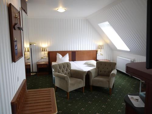 a bedroom with a bed and two chairs at Landhotel Schwarzer Adler in Sülzetal