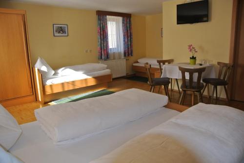 a room with two beds and a table and a dining room at Gasthof Zum Stollhofer in Inzing