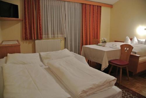 a hotel room with two beds and a table at Gasthof Zum Stollhofer in Inzing