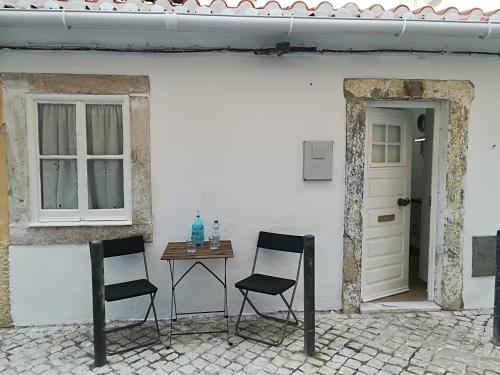 two chairs and a table in front of a white building at Casinhas da Ajuda nº25 in Lisbon