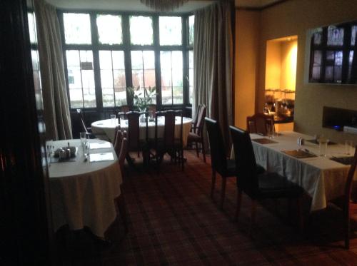 a dining room with tables and chairs and windows at Braehead Guest House in Inverness