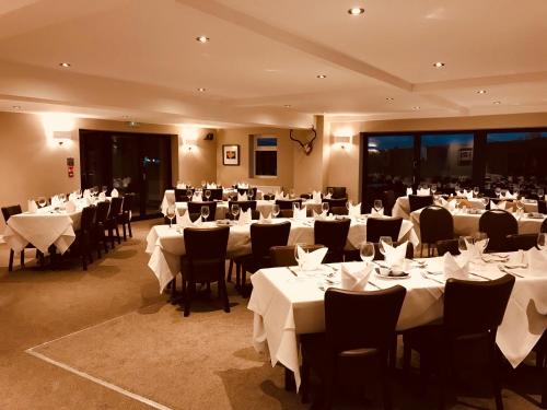 a banquet hall with white tables and chairs at The Twice Brewed Inn in Bardon Mill