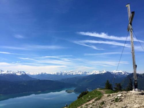 a cross on top of a mountain overlooking a lake and mountains at Hotel Karwendelblick in Urfeld
