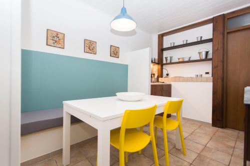 a kitchen with a white table and yellow chairs at B&B Il Viottolo in Noci