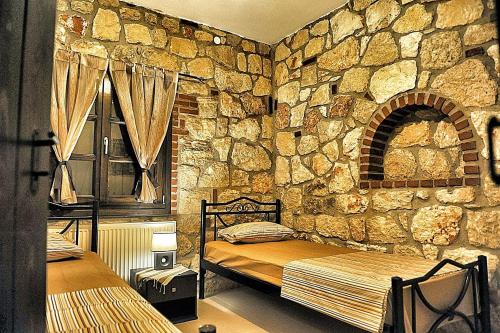 プサコウディアにあるSunstone Villasの石壁のベッドルーム1室(ベッド2台付)