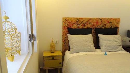 um quarto com uma cama com uma cabeceira em madeira e uma mesa em Casinhas da Ajuda nº 27 em Lisboa