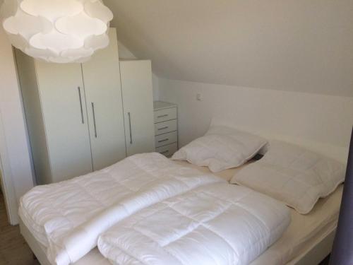 a bedroom with two white beds and a white cabinet at DHH Claire_SAWO in Ostseebad Karlshagen