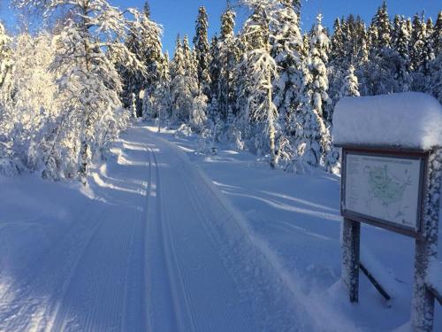 a road covered in snow with a sign and trees at Mieps Huset Dalarna Holiday in Kullen