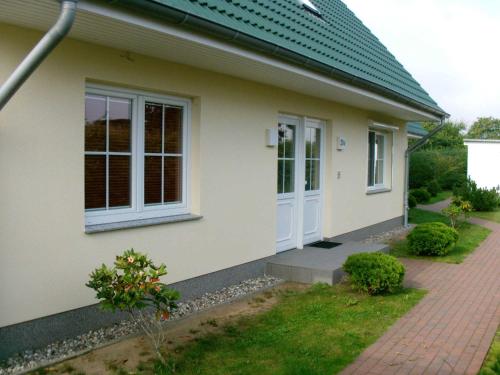 une maison avec des portes blanches et un trottoir en briques dans l'établissement Fewo Dat Ole_ZECH, à Karlshagen