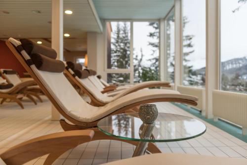 a room with chairs and a glass table and windows at Sunstar Hotel Arosa in Arosa