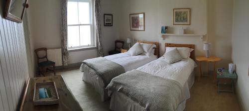 a bedroom with two beds and a table and a window at Uig Lodge in Uig