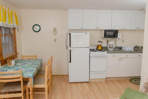 a kitchen with a white refrigerator and a table at Oceanside Condos in Dennis Port