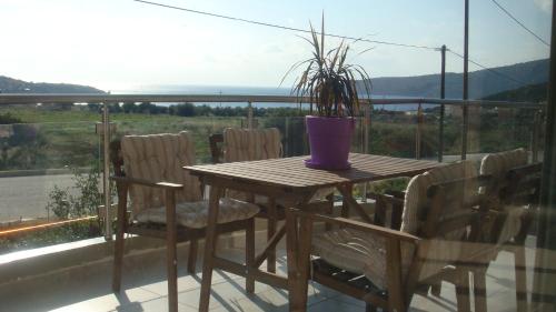 a wooden table with chairs and a potted plant on a balcony at Sandra's Sea View at Sounio in Sounio