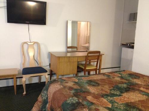 Habitación de hotel con cama, escritorio y espejo. en Pleasant Manor Motel, en Collingwood