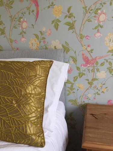 a bed with a gold pillow and floral wallpaper at Black Swan Inn in Masham