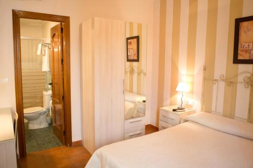 a bedroom with a bed and a bathroom with a toilet at Pensión y apartamentos El Taxi in Casabermeja