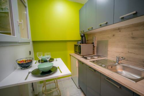 トロワにあるAppartement HYPER CENTRE avec WIFIの緑の壁のキッチン(シンク、カウンター付)