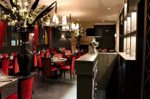 un restaurante con sillas y mesas rojas y una lámpara de araña en LOGIS -Hotel & Restaurant de la Place, en Aunay-sur-Odon