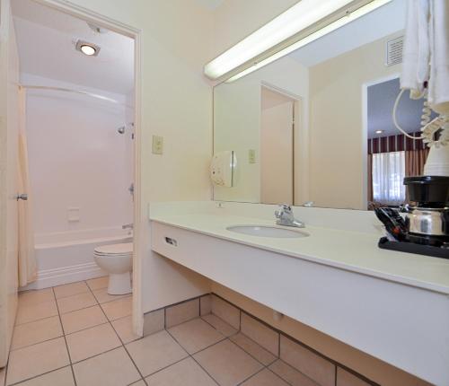 a bathroom with a sink and a toilet and a mirror at Americas Best Value Inn Lubbock East in Lubbock