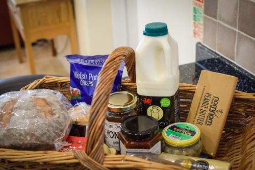 
a basket filled with lots of food next to a bottle of milk at Ysgubor y Coed in Pentyrch
