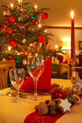 a table with two wine glasses and a christmas tree at Hotel Behringer's Traube in Badenweiler