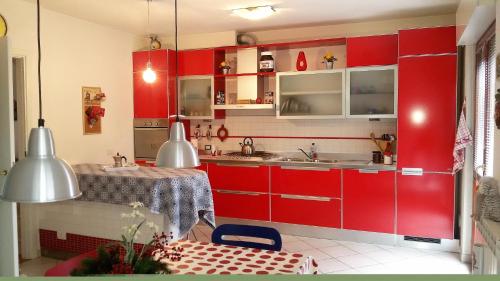 eine rote Küche mit einem Waschbecken und einem Tisch in der Unterkunft Casa Arcobaleno in Siena