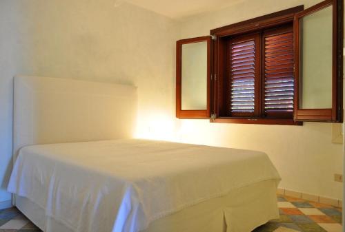 ein Schlafzimmer mit einem weißen Bett in einem Zimmer mit einem Fenster in der Unterkunft Villa Le Meraviglie in San Vito lo Capo