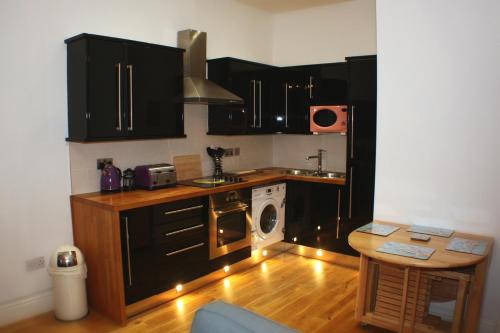 a kitchen with black cabinets and a washer and dryer at The Lookout in Helensburgh