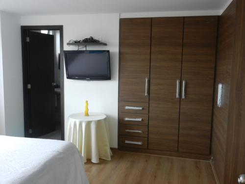 1 dormitorio con un gran armario de madera y TV en Suit Torre Sofia, en Quito