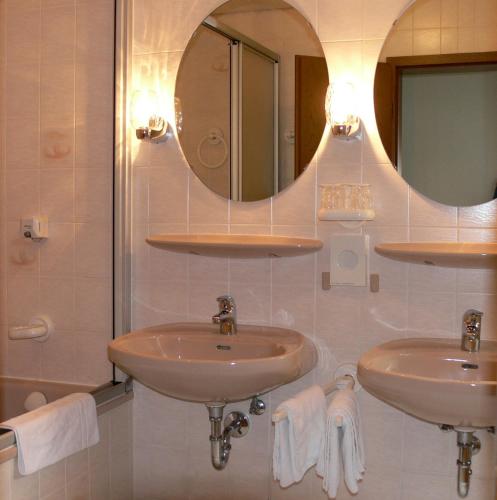 a bathroom with two sinks and a mirror at Hotel Quellenhof in Bad Breisig