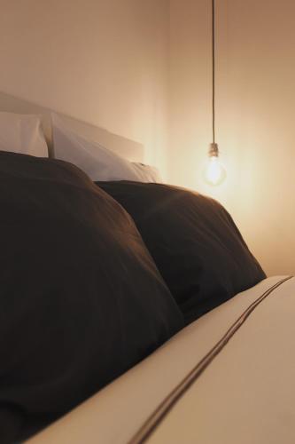Cama con almohada negra y luz en Lost Apartments, en Oporto