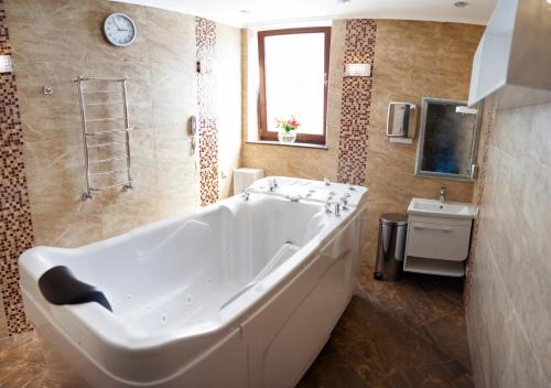 Una gran bañera blanca en un baño con lavabo. en Shato Hotel ШАТО, en Chervonograd