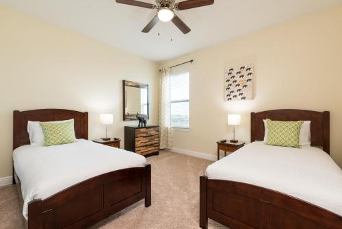 a bedroom with two beds and a ceiling fan at Luxury Dreams Disney Home with Private Pool and Spa in Orlando