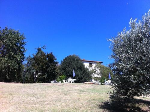 a house with chairs and umbrellas in a field at Agriturismo Il Palazzaccio in Galliano