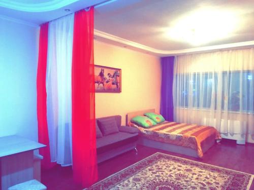 een slaapkamer met een bed, een bank en een raam bij Chupa Chups apartment on Dostyk 5/1 str in Astana