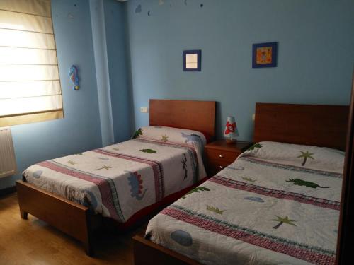 2 Betten in einem Schlafzimmer mit blauen Wänden in der Unterkunft Piso Velázquez in Gijón