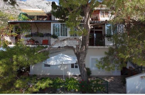 a white house with an umbrella in front of it at Apartments Kassa in Baška Voda