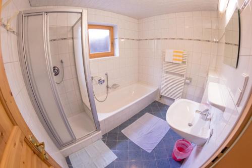 a bathroom with a shower and a tub and a sink at Landhaus Alpenrose in Mayrhofen