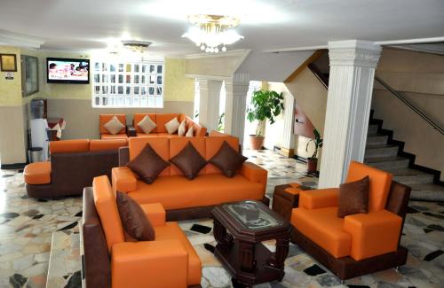 una sala de estar con muebles de color naranja y una escalera. en Hotel el Caimito, en Villavicencio