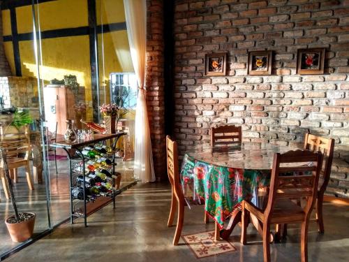 d'une salle à manger avec une table, des chaises et un mur en briques. dans l'établissement Reduto do Alto, à Búzios