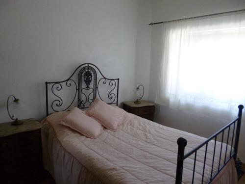 a bedroom with a bed with white sheets and a window at Casa de Santana in Arneiro