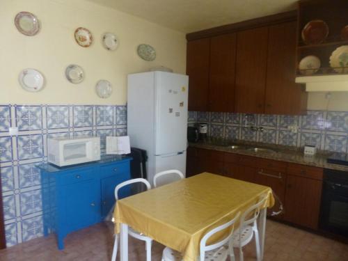 een keuken met een tafel en een witte koelkast bij Casa de Santana in Arneiro