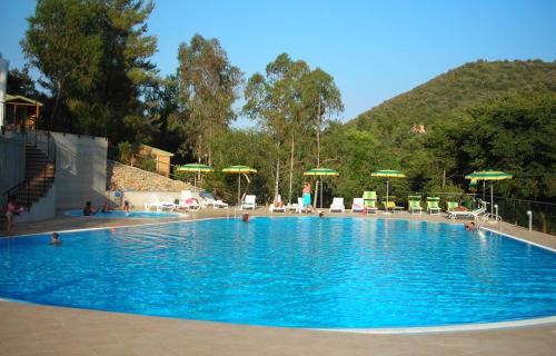 una grande piscina blu con sedie e ombrelloni di Camping Village Canapai a Rio Marina