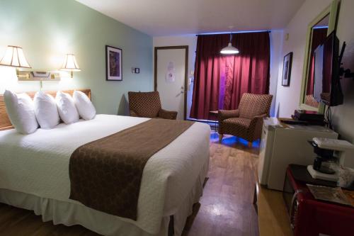a hotel room with a large bed and chairs at La Kris Inn in Bandon