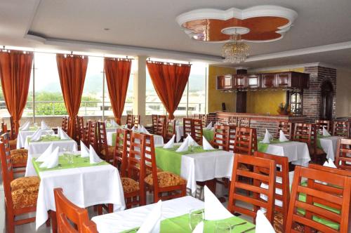 jadalnia z białymi stołami i drewnianymi krzesłami w obiekcie Hotel el Caimito w mieście Villavicencio