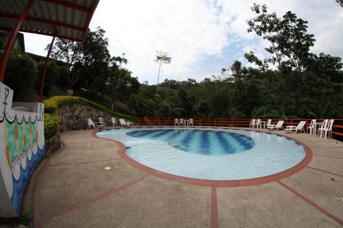 a large swimming pool with white chairs around it at HOTEL LA SELVA Reserva in La Vega