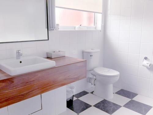 a white bathroom with a sink and a toilet at The International Motel Apollo Bay in Apollo Bay
