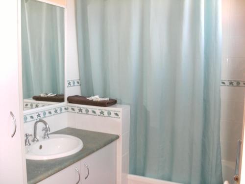 baño con lavabo y cortina de ducha en Regatta Point Holiday Park en Bermagui